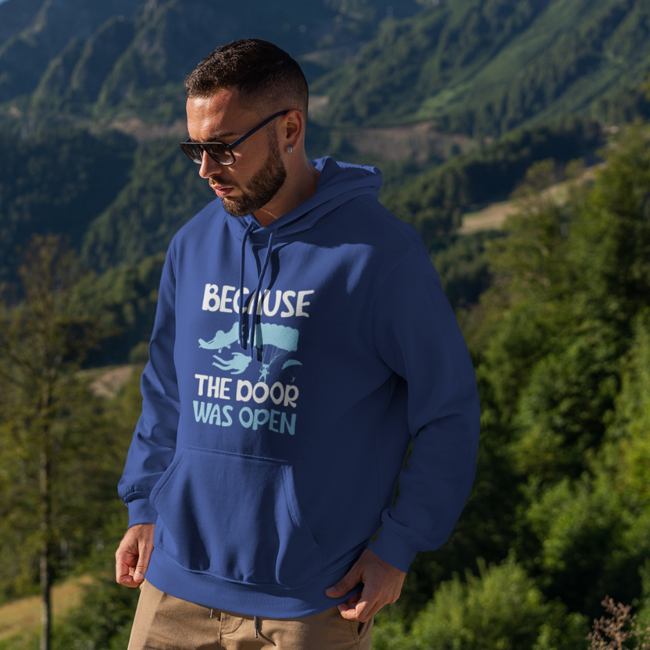 A man wearing a royal blue hoodie with 'Because the door was open' themed design, adorned with a parachute, and sporting sunglasses.