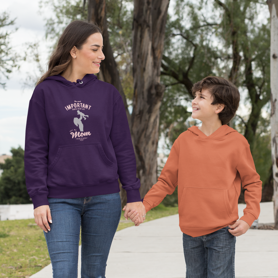 A mother, clad in a purple hoodie with the inscription 'The most important people in my life, they call me mom,' walks alongside her son on a serene journey, epitomizing the essence of maternal love and devotion